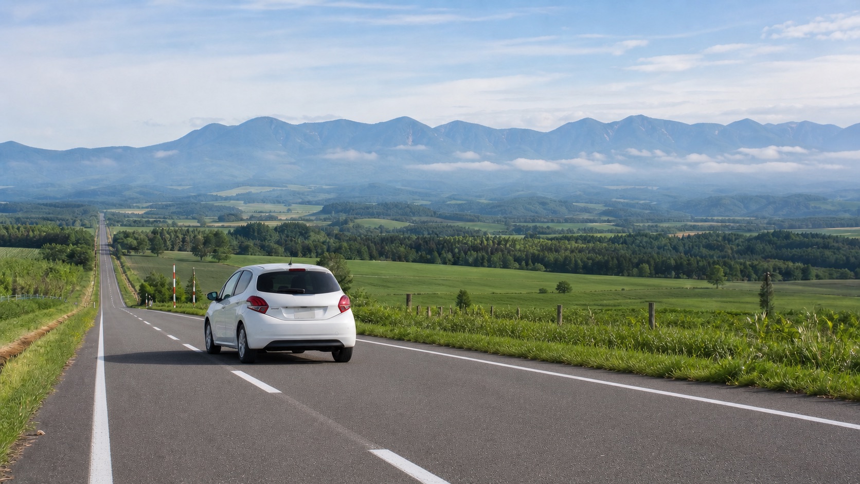 Compact rental car driving on the left through rural Hokkaido