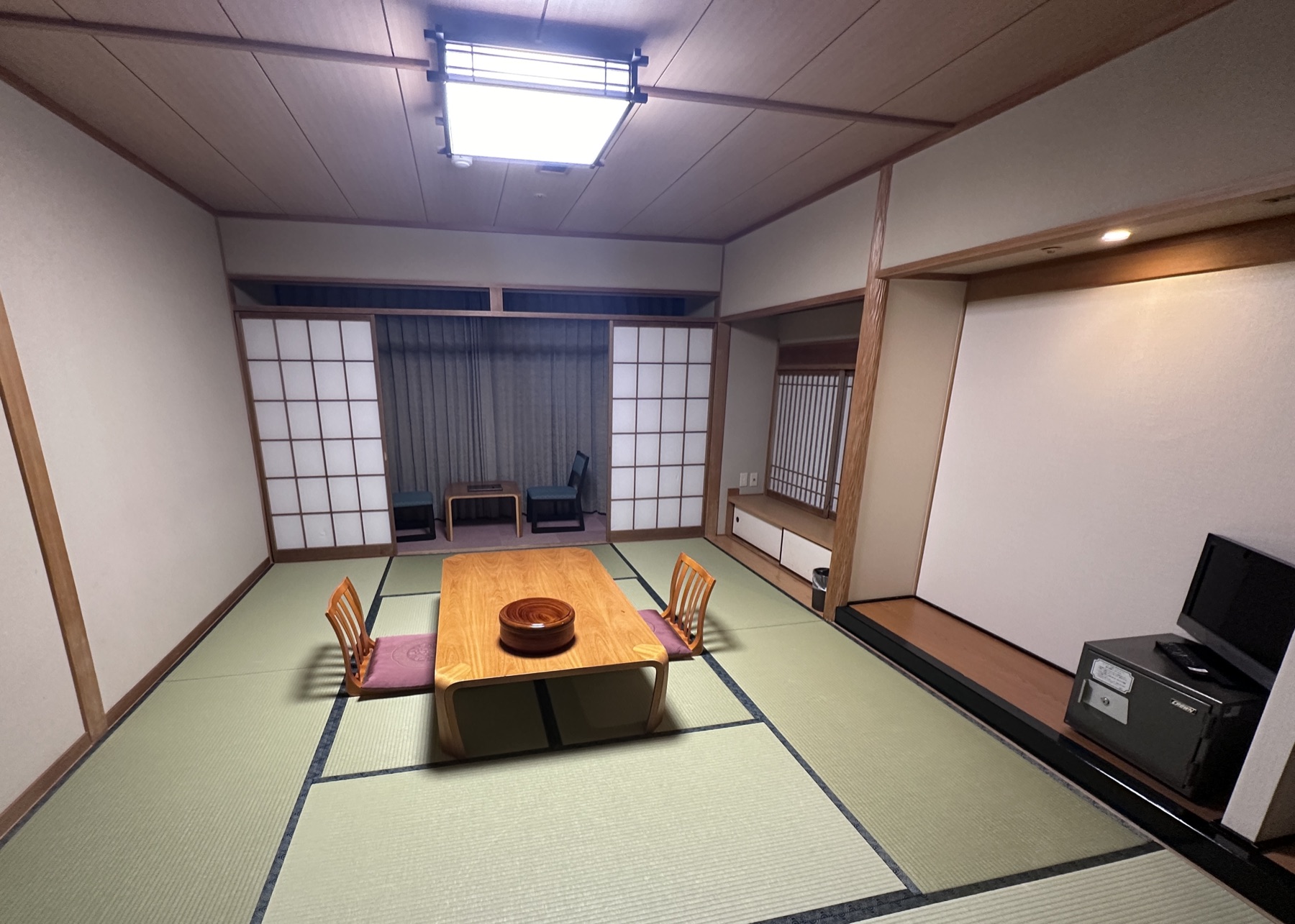 A Japanese ryokan guest room with tatami, shoji screens and a low table