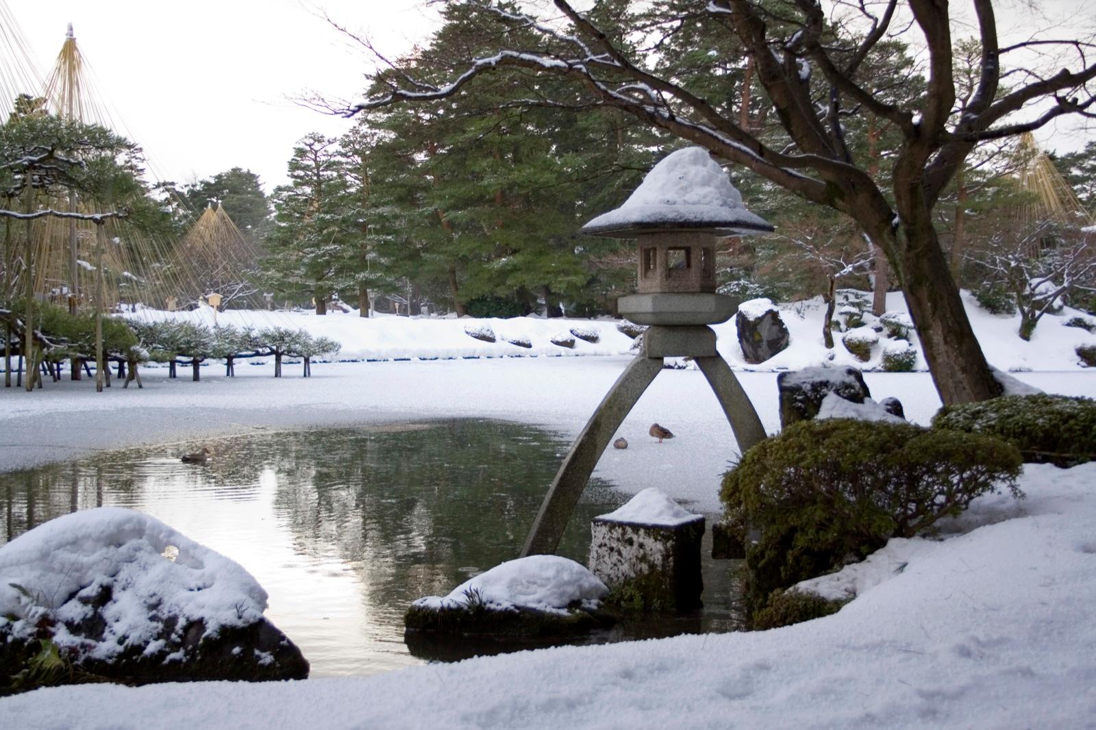 Snow covering the stone lantern, pond and pines of Kenrokuen Garden in Kanazawa