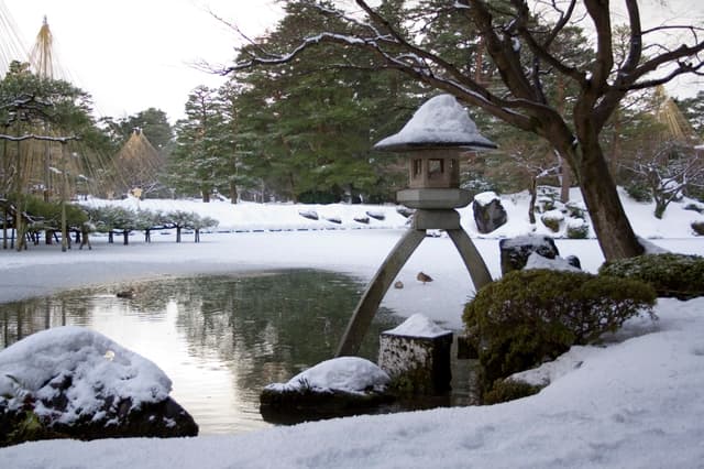 Snow covering the stone lantern, pond and pines of Kenrokuen Garden in Kanazawa